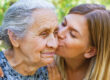 young woman caregiver kissing grandma