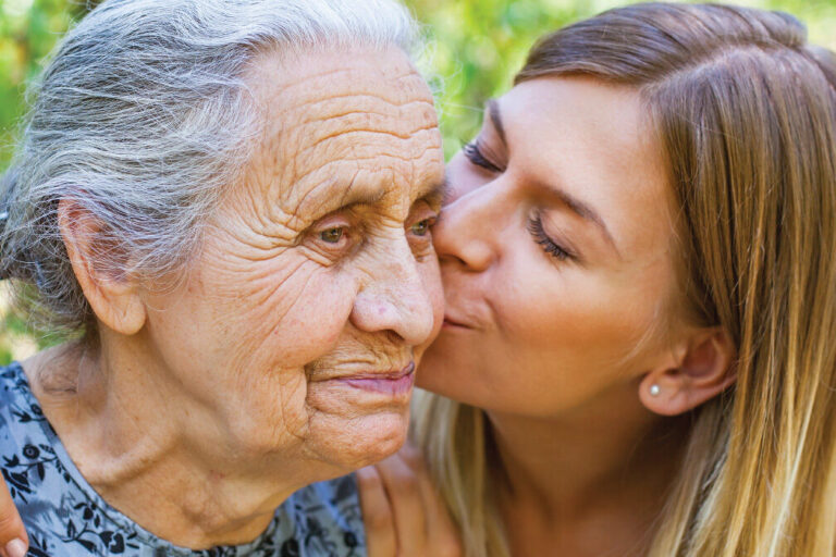 young woman caregiver kissing grandma