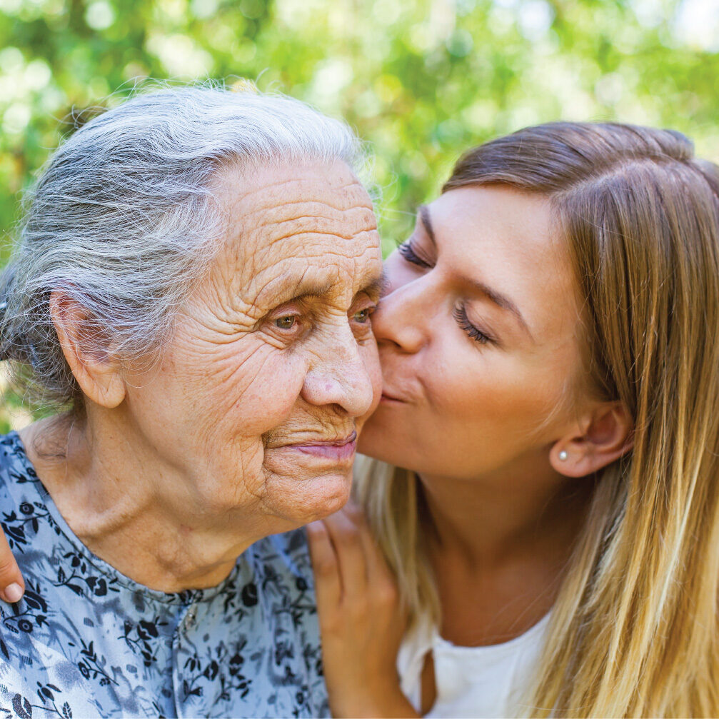 young woman caregiver kissing grandma